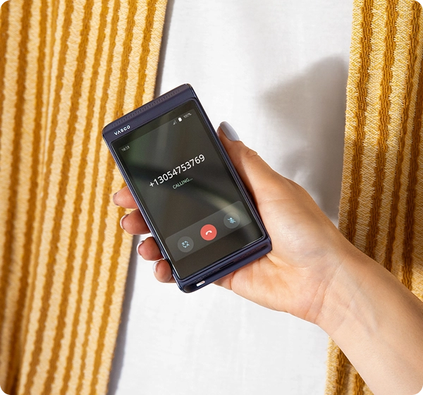 Henkilö, jolla on Vasco Translator Q1 -laite. Näytöllä näkyy puhelutoiminto, jossa on puhelinnumero, ”Calling”-tila sekä keskustelutila.