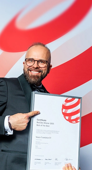 Vasco Electronicsin toimitusjohtaja pitelee Red Dot -palkintoa ja esittelee palkittuja laitteita.